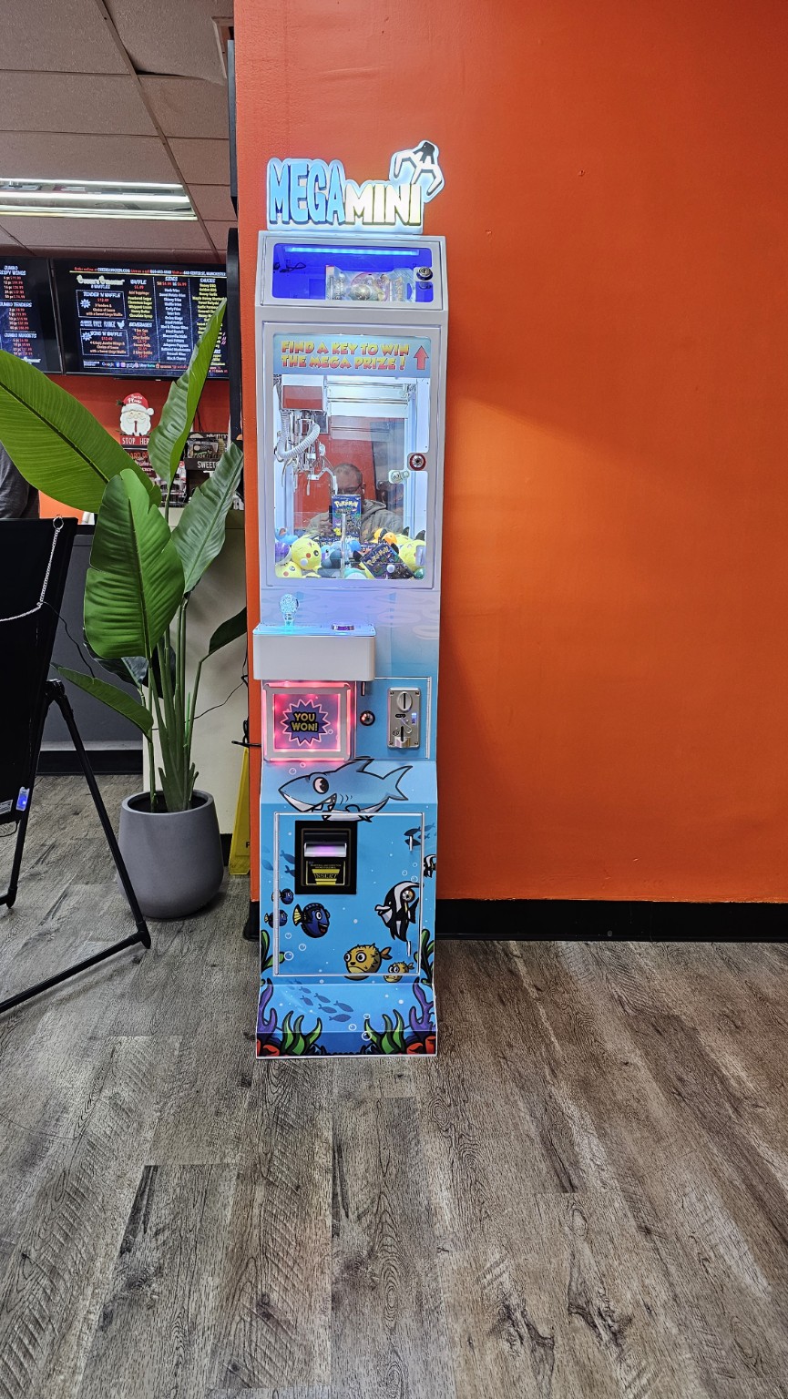 Real Mega Mini claw machine placed inside a business, with colorful ocean artwork and illuminated prize chambers