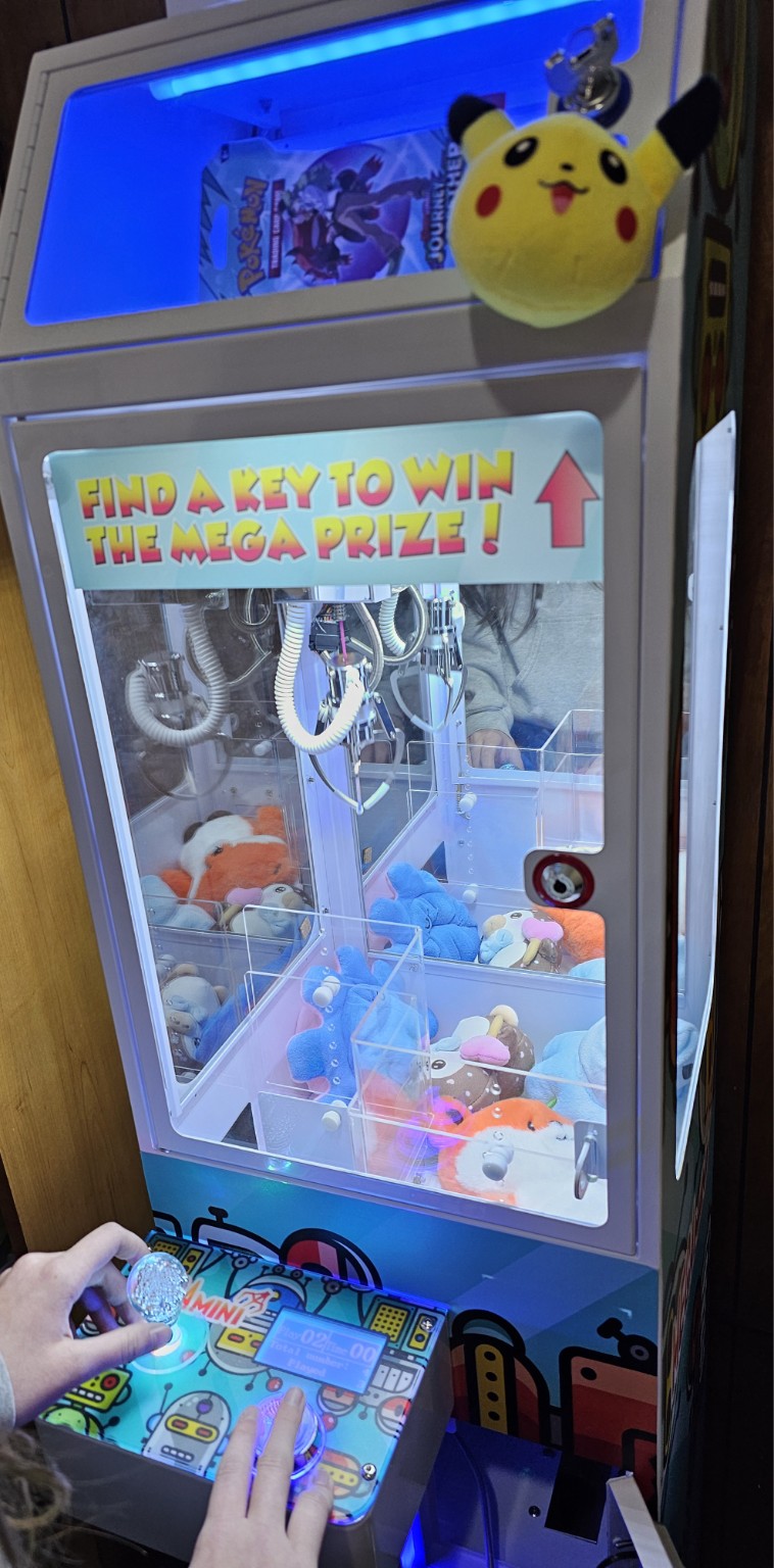 A customer using the illuminated controls of a real Mega Mini claw machine